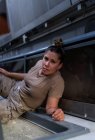 Mujer soldado mirando a la cámara mientras yacía en el suelo del transporte militar contemporáneo - foto de stock