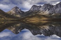 White clouds floating over mountain ridge and calm surface of Embalse del Casares lake in Leon, Spain — Stock Photo