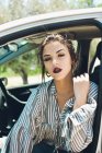 Portrait of pretty girl sitting in the car's chair while getting the sun's rays on her face — Stock Photo