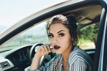 Porträt eines hübschen Mädchens, das im Stuhl des Autos sitzt und die Sonnenstrahlen auf ihr Gesicht bekommt — Stockfoto
