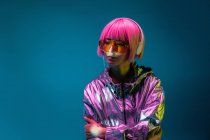 Giovane donna asiatica con elegante taglio di capelli rosa e scintillante giacca d'argento in piedi e ascoltare musica — Foto stock