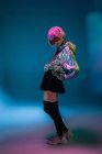 Jeune femme asiatique avec coupe de cheveux rose élégant et veste argentée étincelante posant tout en écoutant de la musique — Photo de stock