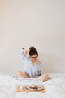 Портрет женщины, растянувшейся, сидя на кровати перед подносом со здоровой пищей — стоковое фото