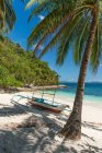 Живописный вид на песчаный берег с лодкой и пальмой на фоне джунглей и голубого неба — стоковое фото