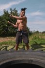 Muscular preto cara martelando pneu no ginásio ao ar livre — Fotografia de Stock