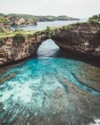 Paesaggio di tranquilla baia tropicale blu dietro l'arco naturale di scogliera nel paesaggio tropicale, Bali — Foto stock