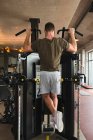Muscular guy doing pull ups on exercise machine — Fotografia de Stock