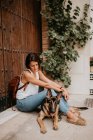 Lässige junge Frauen sitzen mit entzückendem Schäferhund auf Betonpflaster — Stockfoto