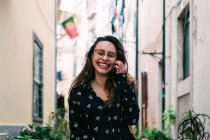 Young laughing brunette walking on street of old city and looking at camera — Stock Photo