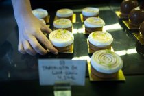 Mãos de pessoa irreconhecíveis segurando um delicioso bolo de merengue em uma exibição de padaria — Fotografia de Stock