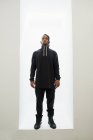 Afro-americano homem no preto roupas com trançado cabelo de pé isolado no branco fundo — Fotografia de Stock
