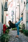 Jeune femme mince et décontractée s'étirant sur la rue de la vieille ville tout en dansant gracieusement — Photo de stock