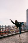 Lässige junge Frau fliegt im Spagat beim Tanzen auf dem Hintergrund der Küstenstadt — Stockfoto