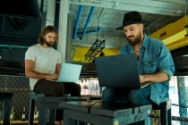 Молоді красиві бородаті чоловіки серйозно і концентрувалися на роботі друку на ноутбуках на колінах — стокове фото