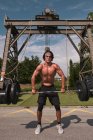 Muscular guy with barbell in outdoor gym — Stock Photo