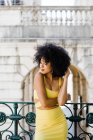 Sensual African American woman in yellow suit standing on urban background — Stock Photo
