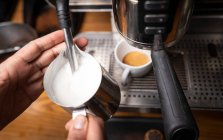 From above crop hands of professional employee preparing cappuccino with pattern on top in coffee shop — Stock Photo