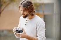 Jovem barbudo bonito homem em roupas casuais tirando foto na rua — Fotografia de Stock