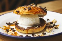Sorvete doce fresco em hambúrguer de chocolate com migalha de noz apetitoso na placa branca — Fotografia de Stock