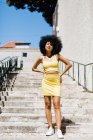 Afrikanisch-amerikanische Frau im gelben Anzug steht auf der Treppe und blickt in die Kamera vor urbanem Hintergrund — Stockfoto