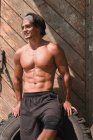 М'язистий красивий чоловік позує в спортзалі перед дерев'яними дверима — стокове фото