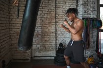 Чорний хлопець бокс в гранжевому спортзалі з цегляними стінами — стокове фото