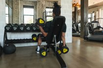 Hombre fuerte haciendo ejercicio con los pepinos en el gimnasio. - foto de stock