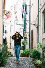 Young casual brunette walking on cobblestone street of old city — Stock Photo