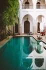Las aguas tranquilas claras de la piscina en la terraza del balneario exótico con la arquitectura oriental a la luz del sol, Marruecos - foto de stock