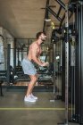 Guy utilizando máquinas de ejercicio en el gimnasio, vista lateral - foto de stock