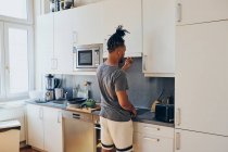 Afro-americano trenzado hombre de pie en la cocina y cocinar - foto de stock