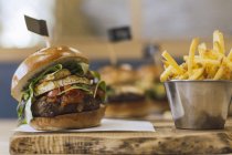 Succosa deliziosa hamburger e patate fritte su tavola di legno — Foto stock