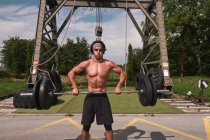 Young bodybuilder with barbell in outdoor gym — Stock Photo