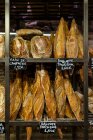 Fresh appetizing baguettes arranged on wooden rack in bakery shop — Stock Photo