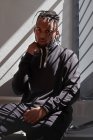 Молодой афроамериканец сидит на металлических перилах и смотрит в камеру — стоковое фото
