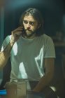 Молодий бородатий красивий чоловік у кафе за вікном розмовляє по телефону — стокове фото