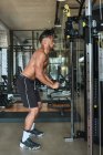 Black guy using exercise machine in gym — Fotografia de Stock