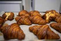 Schöne frisch gebackene Croissants in einem Blech in der Küche drinnen — Stockfoto