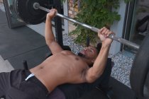From above shirtless African American man exercising with barbell while training in outdoor gym — Fotografia de Stock
