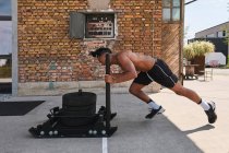 Black guy pulling weights in outdoor gym — Stock Photo