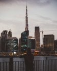 Vista posteriore di persona in piedi su argine contro i grattacieli incandescenti della città di Dubai — Foto stock