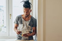 Junger afrikanisch-amerikanischer Mann lehnt auf Fensterbank und liest Buch — Stockfoto