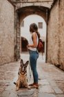 Cute german shepherd standing on cobblestone pavement with owner standing — Stock Photo