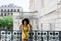 Afrikanische Amerikanerin im gelben Anzug steht und blickt in die Kamera vor urbanem Hintergrund — Stockfoto