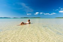 Mujer descansando en el agua en la orilla del mar tropical - foto de stock