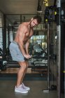 Guy utilizando máquinas de ejercicio en el gimnasio - foto de stock