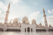 Exterior of white mosque with domes and minarets under bright blue sky, Dubai — Stock Photo