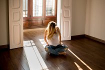 Schwangere sitzt an sonnigem Tag in geräumigem Zimmer auf dem Boden — Stockfoto
