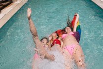 Anonymous lesbians splashing in swimming pool — Stock Photo