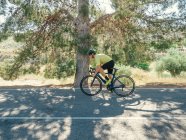 Uomo sano in bicicletta sulla strada di montagna nella giornata di sole — Foto stock